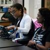 Mother watches daughter use augmentative communication device in classroom